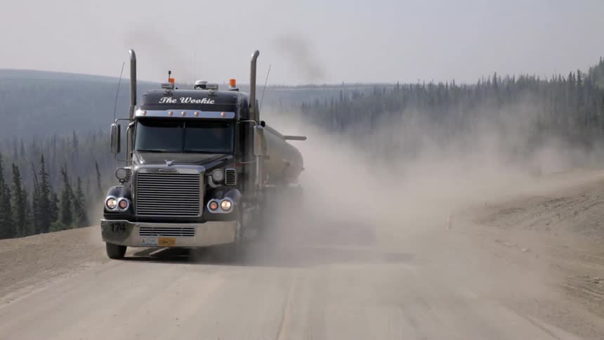 A truck drives down a dusty road
