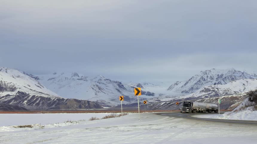 A truck turns around a winding road near a mountain