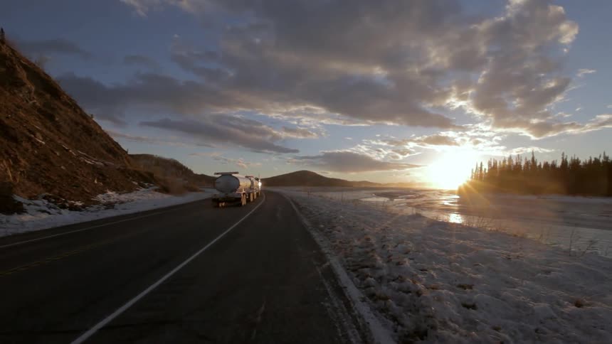 A tanker truck speeds along a road in a snow-covered landscape