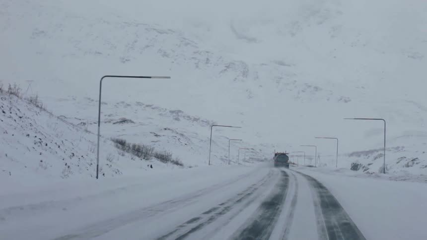 A truck is driving down a snowy road
