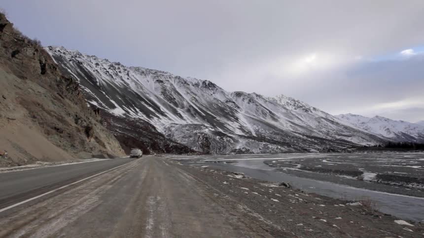 A semi-truck drives in snowy mountains