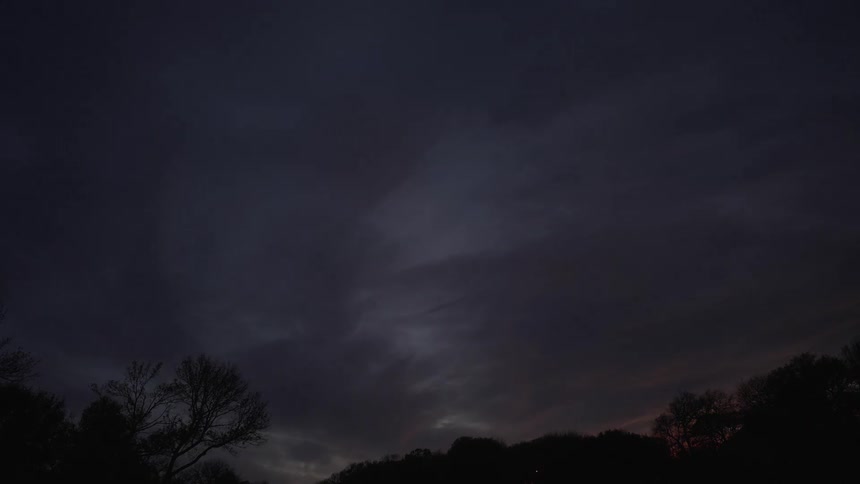 A time lapse of a cloudy sky reveals the transition from evening to nighttime