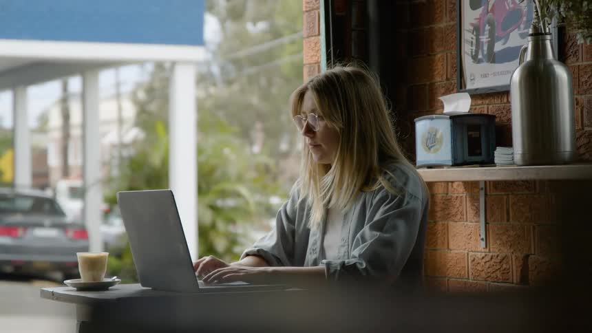 A woman is typing on a laptop in the cafe