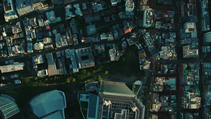 Aerial view above downtown buildings and skyscrapers as traffic moves on the street