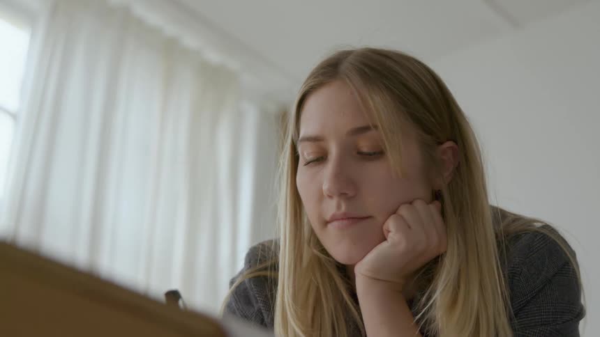 A teenager at home thinks and writes on paper