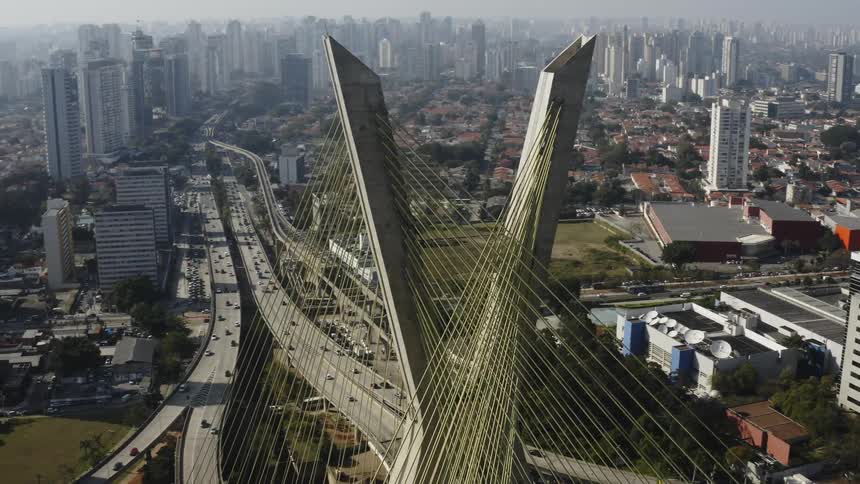 An aerial view of a city with tall buildings, cable stayed bridge on foreground
