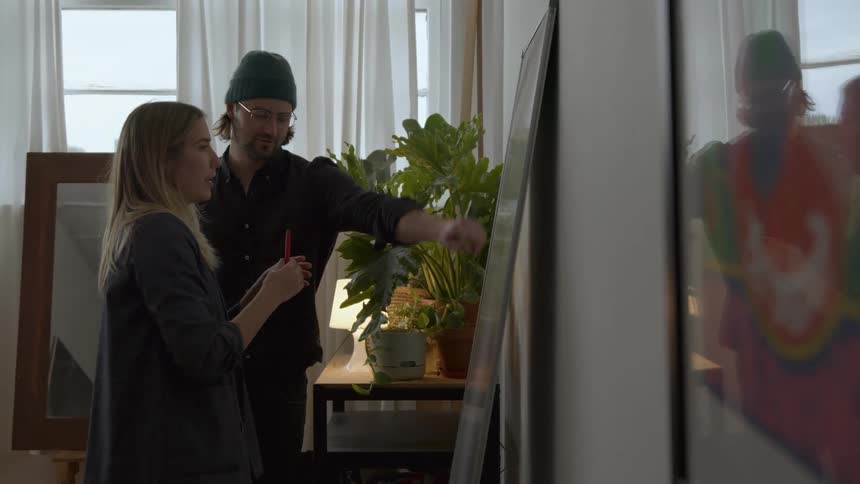 Colleagues chat while standing in front of a whiteboard in the office