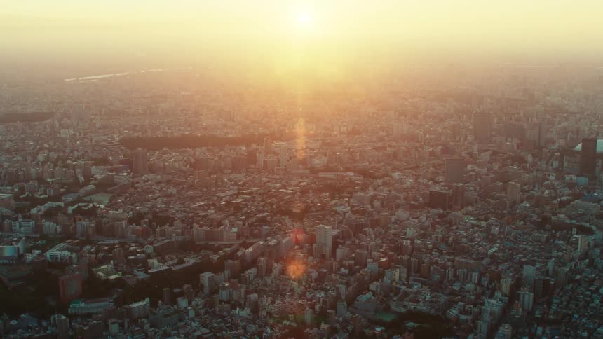 The sun shines brightly in the hazy sky over a city filled with buildings