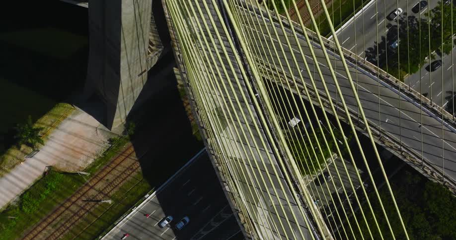 An aerial view of cars driving across and under a bridge