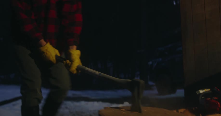 A man chops firewood in the snow