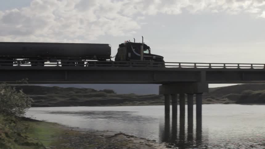 A truck driving across a bridge over a river