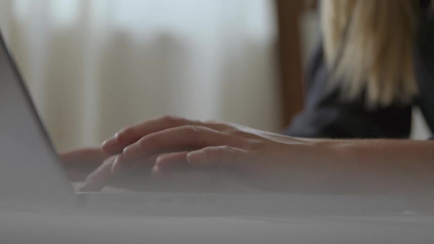 A woman is typing on her laptop