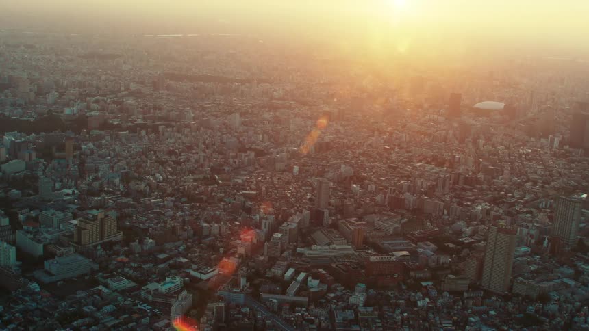 Sun glares from horizon over sprawling city of hazy day