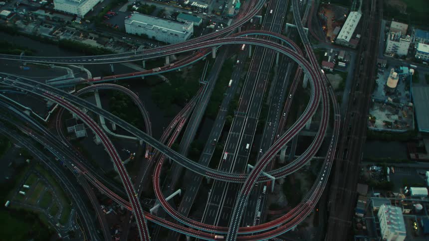 Arial view of traffic moving on a winding highway intersection and the surrounding buildings in town