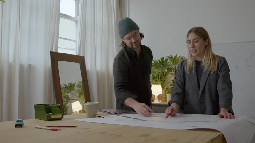A man and woman look at blue prints