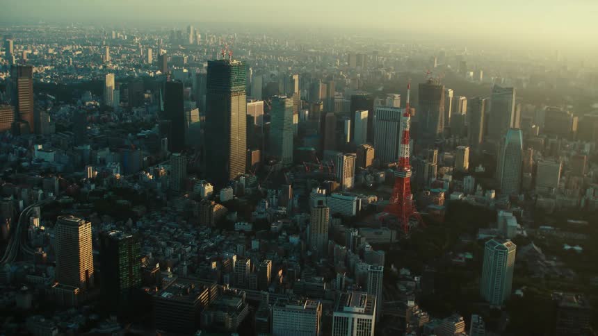 An aerial view of tall skyscrapers and buildings in a city at sunrise