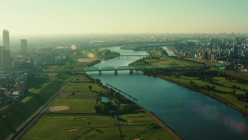 An aerial view of a river flowing through an urban park at sunrise