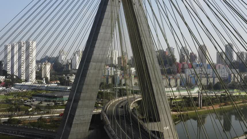 An aerial view of cars traveling over a suspension bridge in a large city
