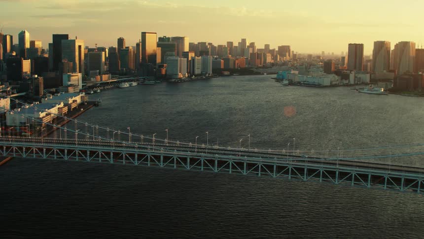 An aerial view of a large city bridge with skyscrapers in the distance