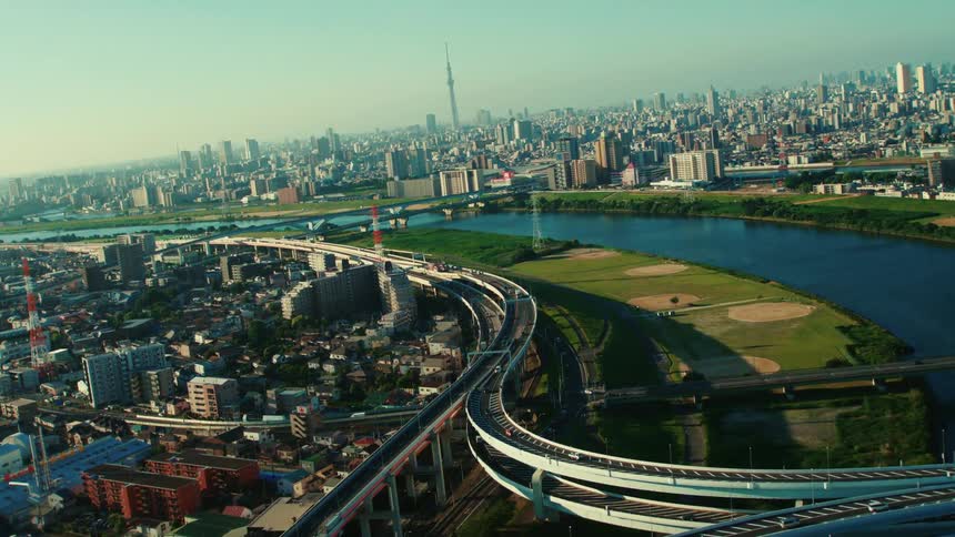 An aerial view of a river running through a city with high rise office buildings and cars driving