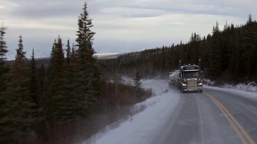 A semi drives on a snowy road