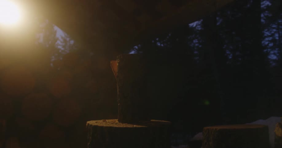 A person chopping wood outside on a log at night
