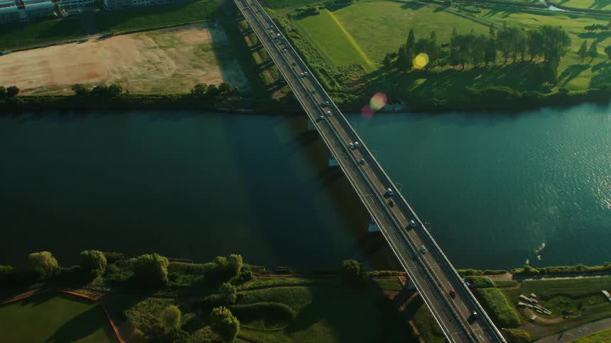 Traffic crosses river on multi lane bridge passing over parks near city
