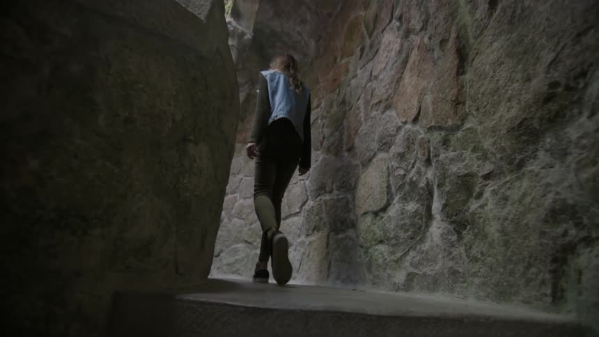 A woman walks in a stone building