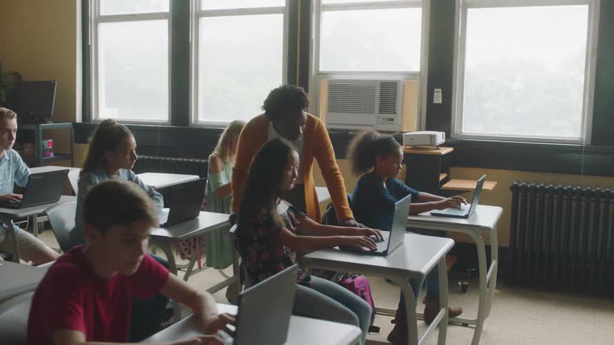 Woman teaches students who are working on laptops