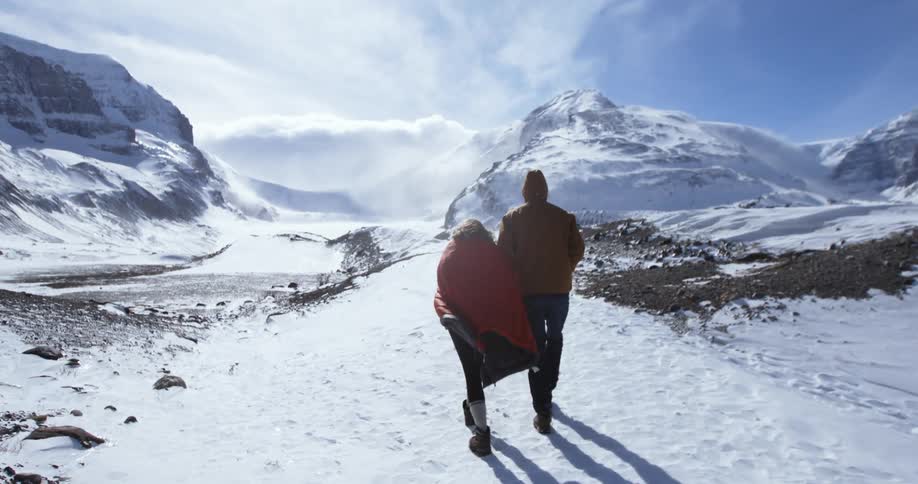 A man and woman climb a snowy mountain