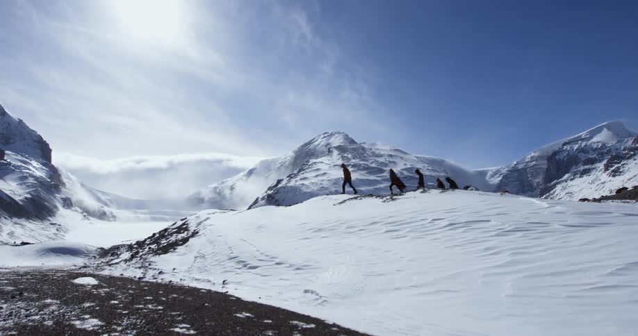 People are hiking over a snow covered mountain range