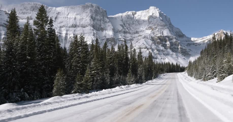 Snowy roadway heading towards some mountains