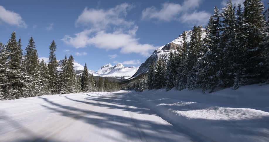 Moving down a road covered with snow and mountains in the distance
