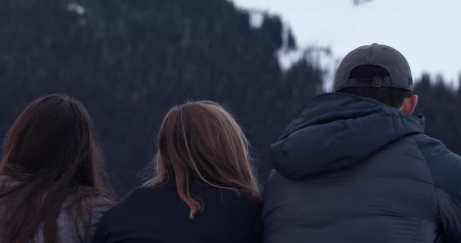 Three people standing together looking at a snowy landscape