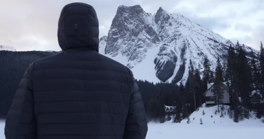 A person stands before a mountain covered with snow
