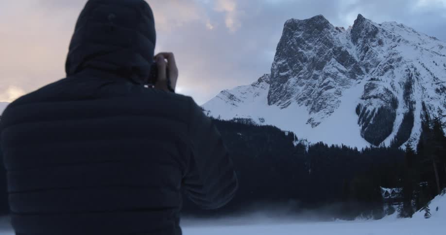 A man takes pictures of a snowy mountain