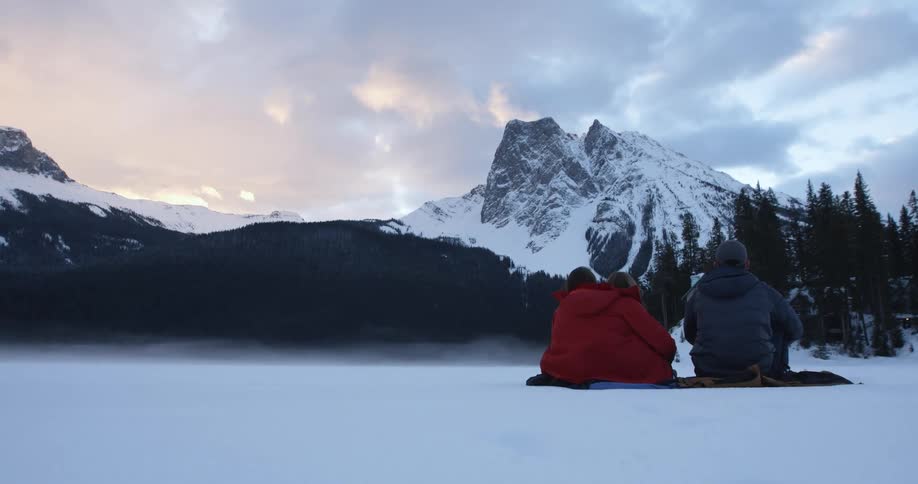 People are sitting on a blanket on a snow covered field