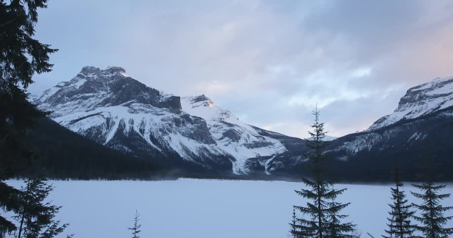View of a lake and snow-covered mountain peak under a cloudy sky