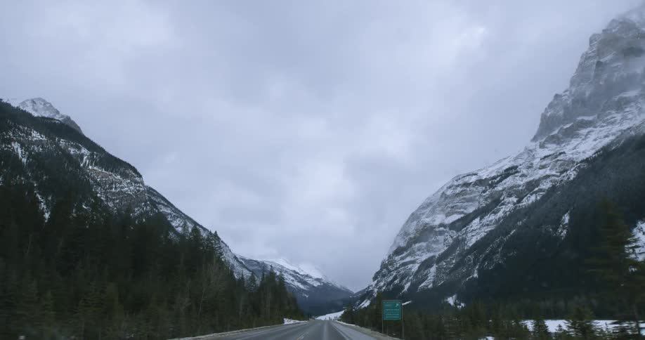 Driving forward along a two lane highway with mountains on either side