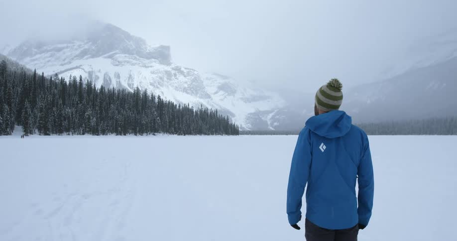 A man looks out at a snowy tree line