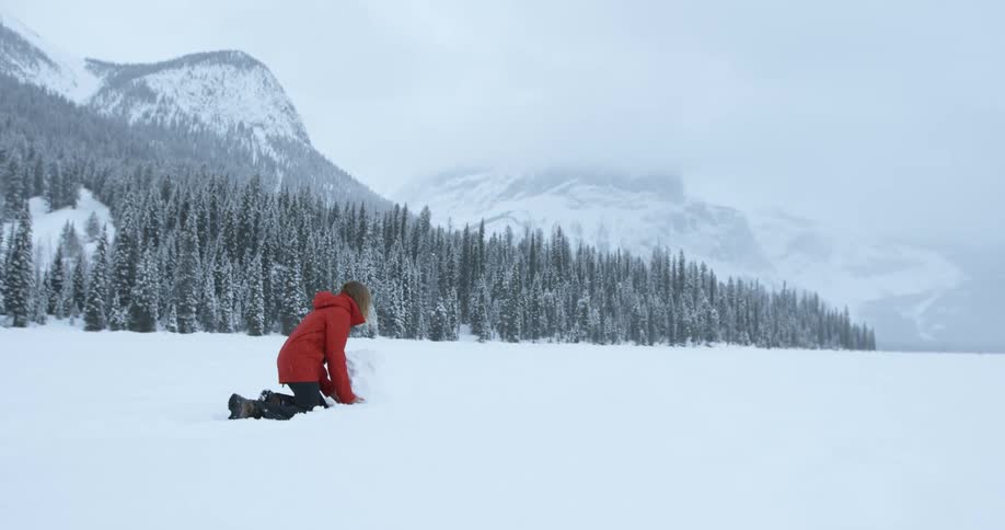 A woman rolls a large snowball