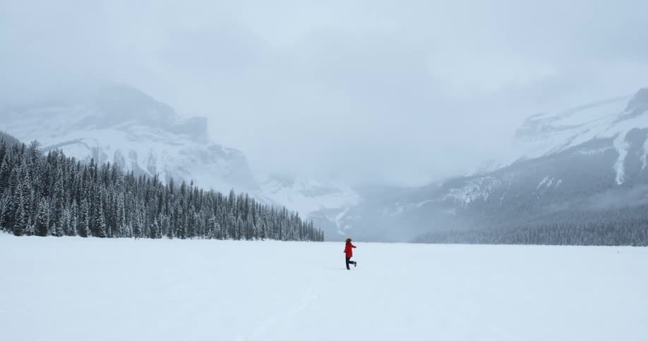 A woman is dancing on a large field covered with snow