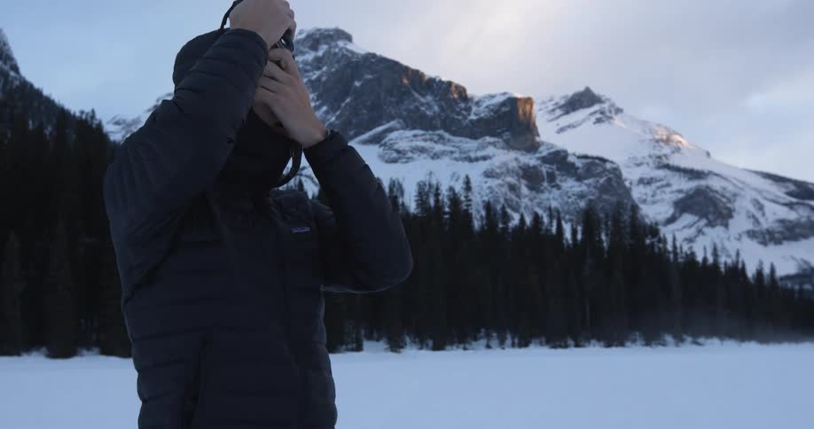 A woman builds a snowman while it snows in the mountains