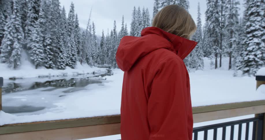 Person in a red coat walking across a snowy bridge