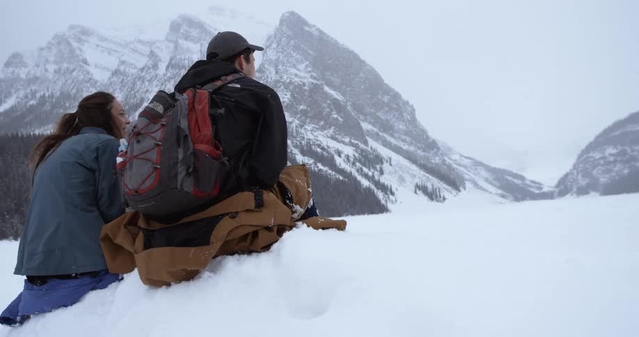 Two people are sitting on snow talking
