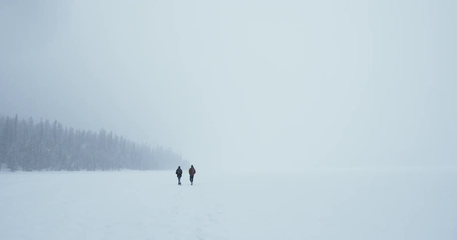 Two people walk in a snowstorm