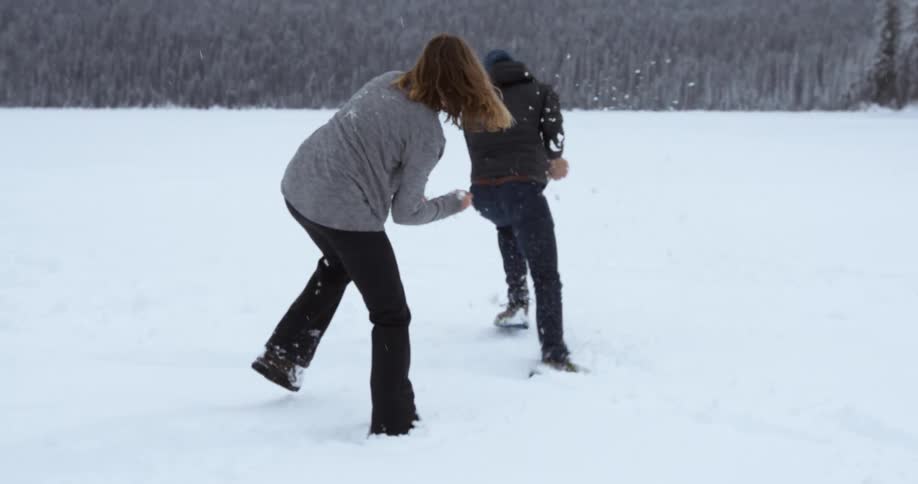 A man and woman have a snowball fight