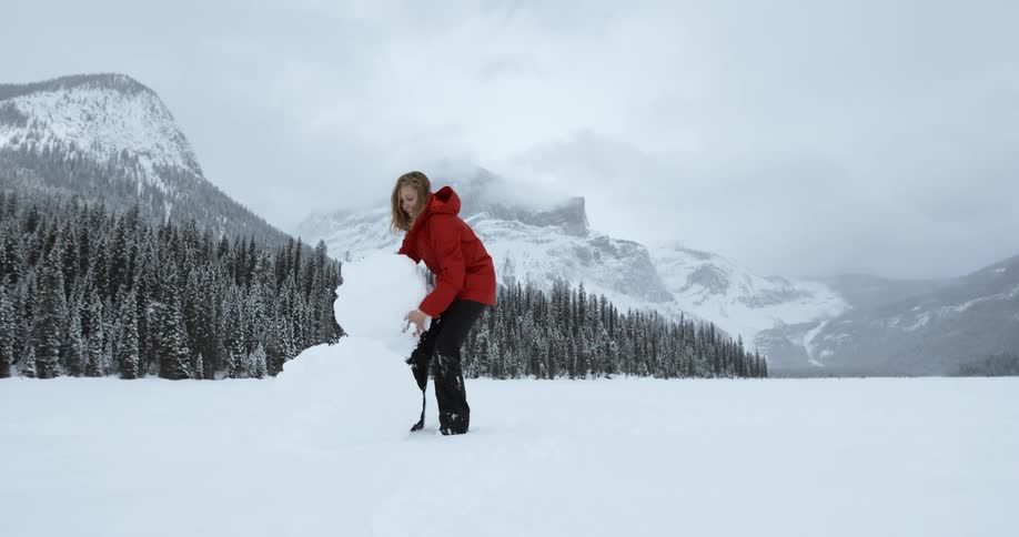 A woman builds a snowman on a winter day
