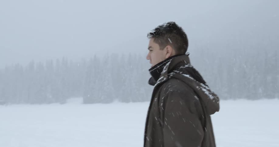 A man is walking outside during heavy snow