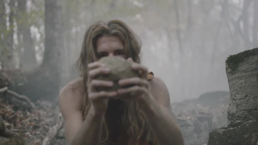 A man picks up a rock from the ground examining it